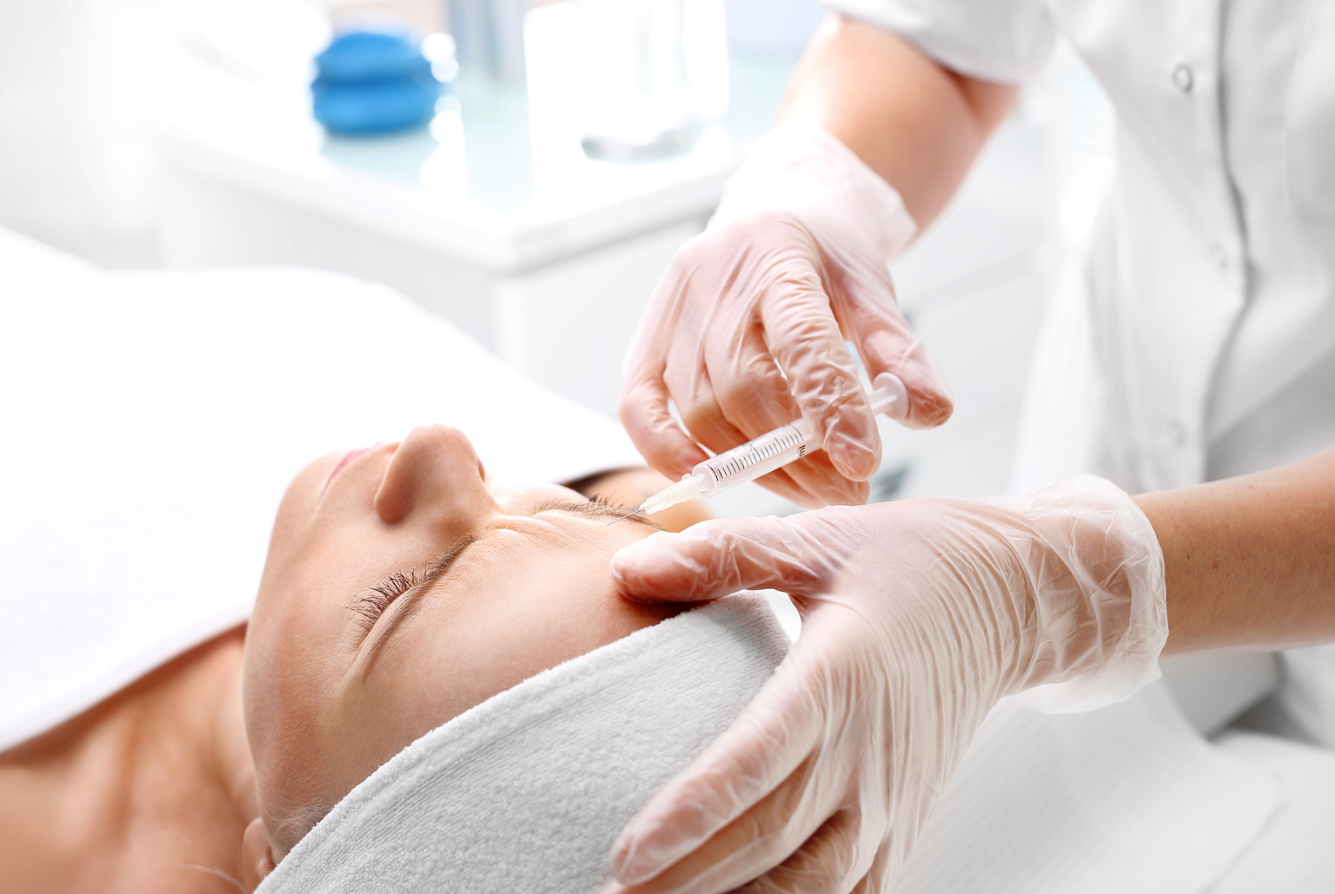 Aesthetician administering anti wrinkle injections to patient